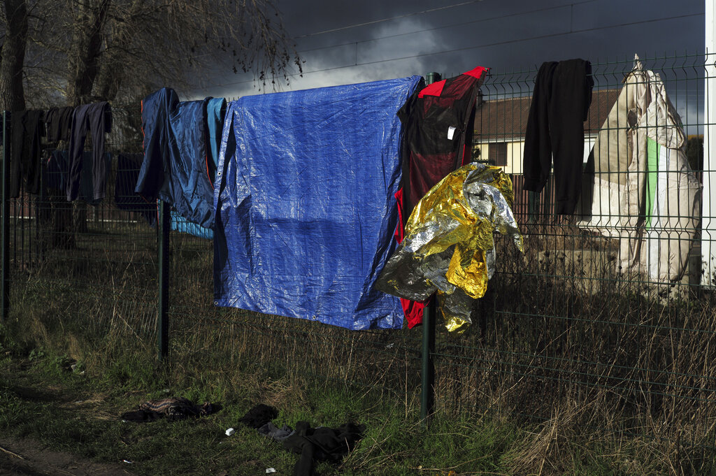 Migrants belongings are hanged on a fence in a makeshift camp outside Calais, northern France, Saturday, Nov. 27, 2021. At the makeshift camps outside Calais, migrants are digging in, waiting for the chance to make a dash across the English Channel despite the news that at least 27 people died this week when their boat sank a few miles from the French coast. (AP Photo/Rafael Yaghobzadeh)