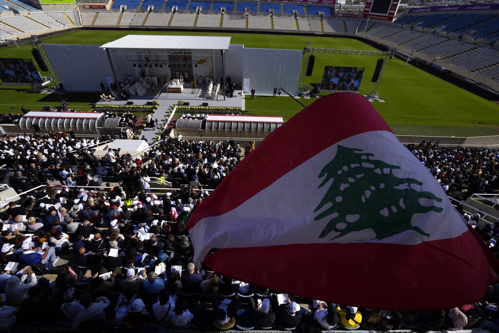 A pilgrim waves a Lebanese flag during a Holy mass by Pope Francis at GSP stadium in Nicosia, Cyprus, Friday, Dec. 3, 2021. Francis is on a five-day trip to Cyprus and Greece by drawing attention once again to his call for Europe to welcome migrants. (AP Photo/Petros Karadjias)