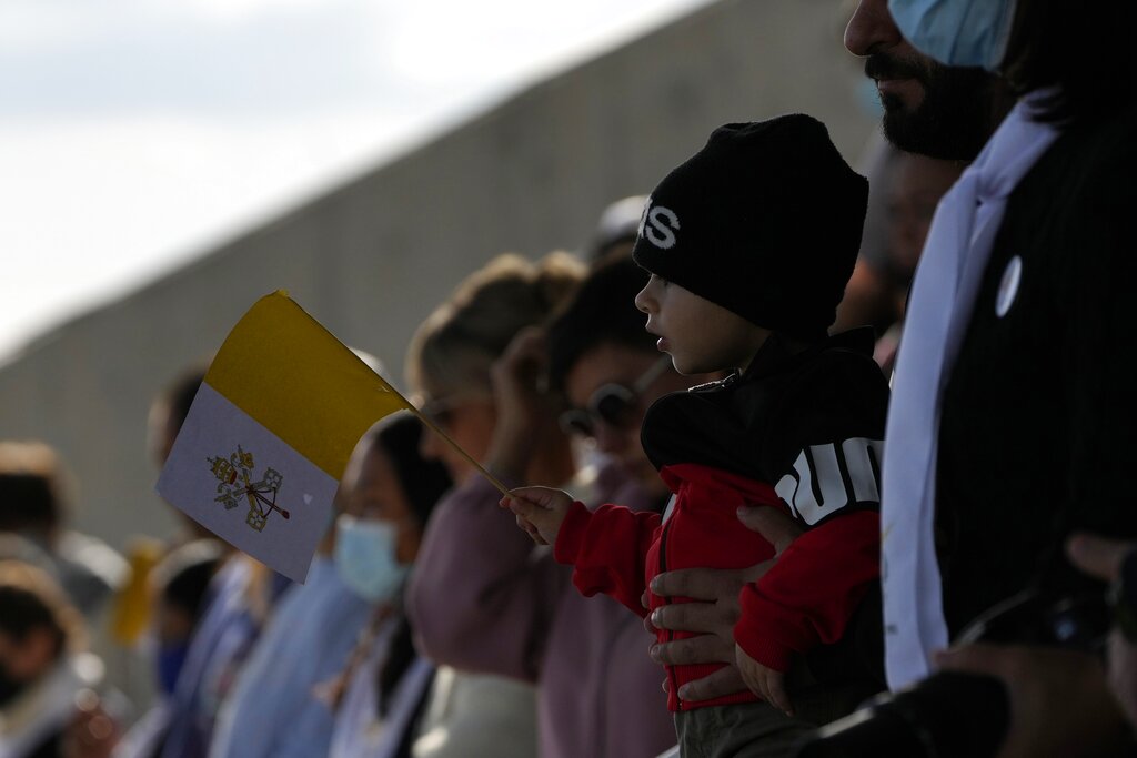 A boy holds a flag of Vatican as pilgrims attend a Holy mass by Pope Francis at GSP stadium in Nicosia, Cyprus, Friday, Dec. 3, 2021. Francis is on a five-day trip to Cyprus and Greece by drawing attention once again to his call for Europe to welcome migrants. (AP Photo/Petros Karadjias)