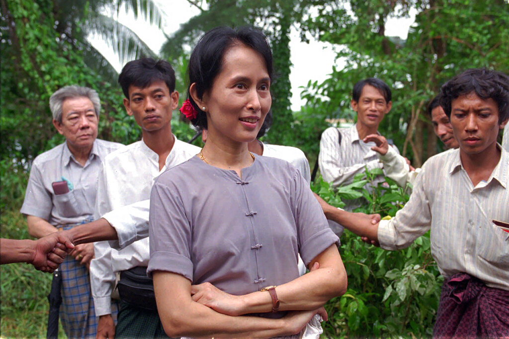 FILE - Nobel Peace Prize winner Aung San Suu Kyi is surrounded by bodyguards and aides in the garden of her house during a press conference following her release earlier in the week after six years under house arrest, Rangoon, Burma on July 14, 1995. A court in Myanmar sentenced the country’s ousted leader, Aung San Suu Kyi, to four years in prison on Monday, Dec. 6, 2021, after finding her guilty of incitement and violating coronavirus restrictions, a legal official said. (AP Photo/Anat Givon, File)