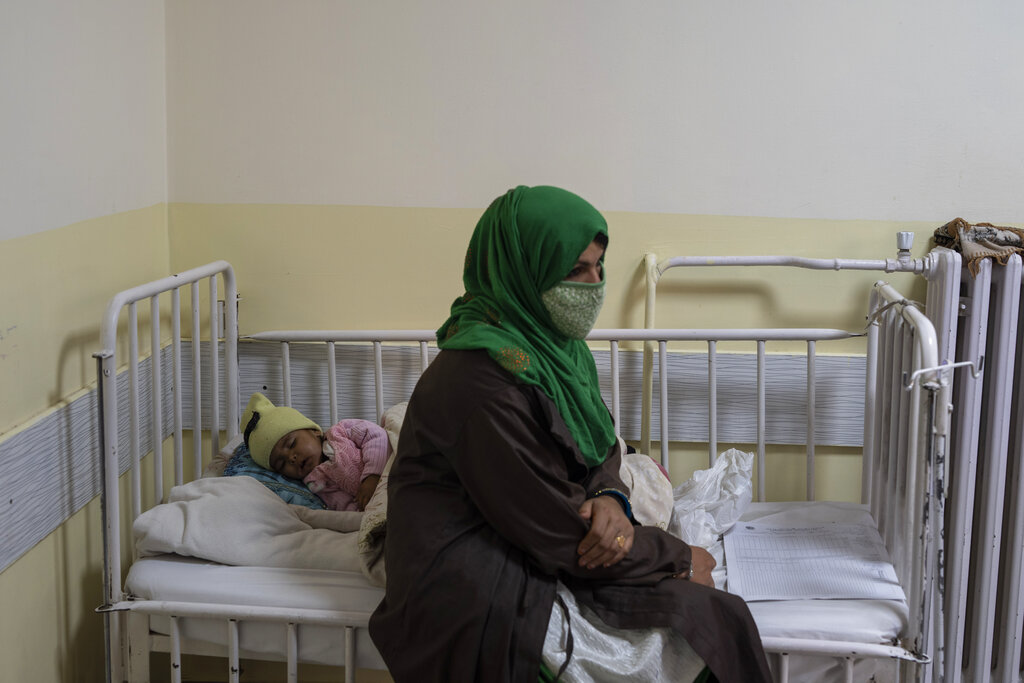 A baby girl sleeps on a bed next to her mother as she undergoes treatment at the malnutrition ward of the Ataturk National Children's Hospital in Kabul, Afghanistan, Thursday, Dec, 2, 2021. According to U.N. figures from early November, almost 24 million people in Afghanistan, around 60% percent of the population, suffer from acute hunger, including 8.7 million living in near famine. (AP Photo/Petros Giannakouris)