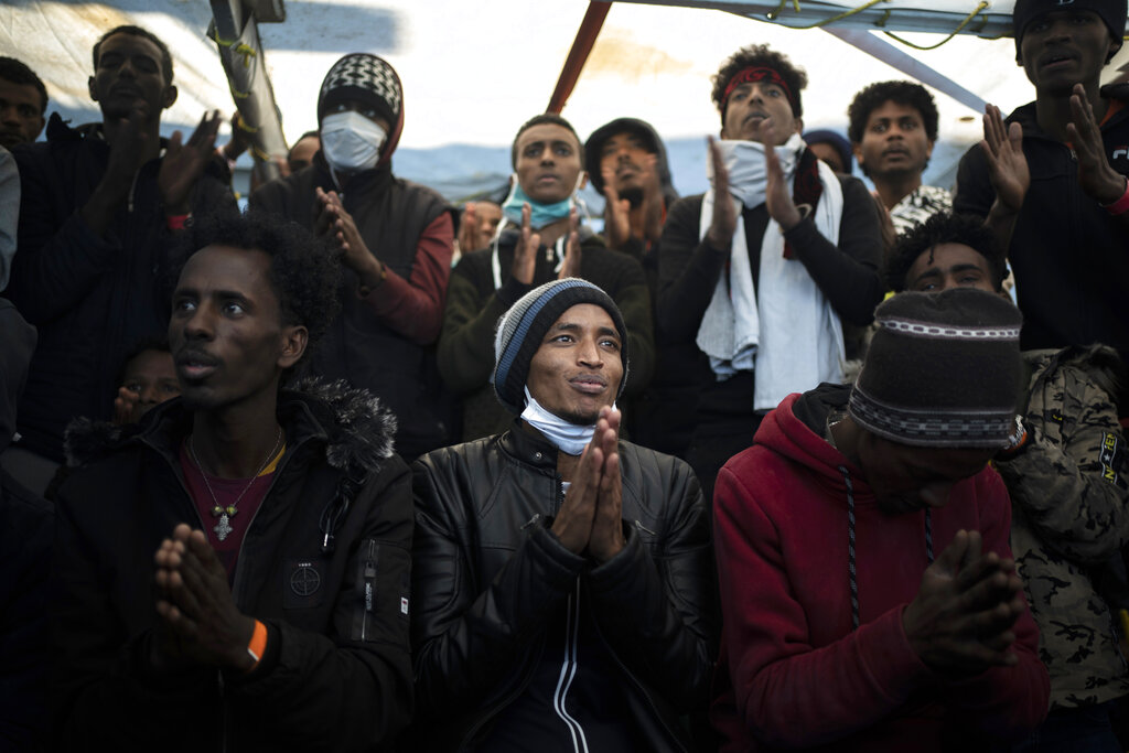 Yohaness, from Eritrea, prays with other migrants as they arrive at the coast of Italy aboard the Spanish vessel Open Arms, on Jan. 4, 2021, after being rescued in the Mediterranean sea. (AP Photo/Joan Mateu)