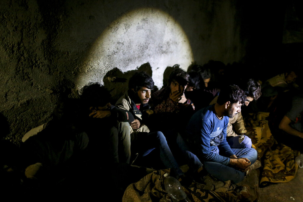 A group of migrants is illuminated by the light of Turkish security forces, who apprehended them in an operation aimed at stemming the recent influx of migration, mainly from Afghanistan, and stopping human trafficking in the border province of Van, Turkey, on Aug. 21, 2021. (AP Photo/Emrah Gurel)