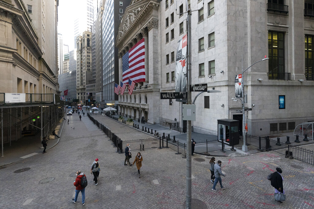 People walk by the New York Stock Exchange, Monday, Nov. 16, 2020, in New York. Stock markets are rallying on news that a second coronavirus vaccine shows promise. (AP Photo/Mark Lennihan)