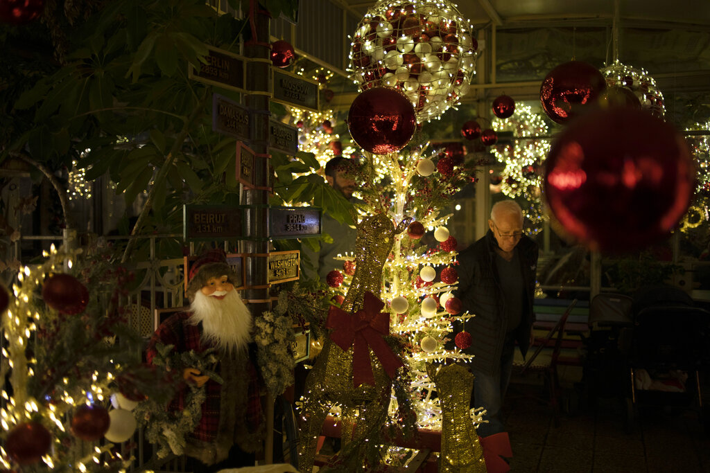 People walk past a Christmas decorated restaurant in Haifa, Israel, Wednesday, Dec. 15, 2021. A spokesman for Christian churches in the Holy Land on Wednesday accused Israel of discriminating against Christian tourists during the normally busy Christmas holiday season. Israel last month closed its borders to foreign tourists in response to the outbreak of the omicron coronavirus variant. (AP Photo/Ariel Schalit)