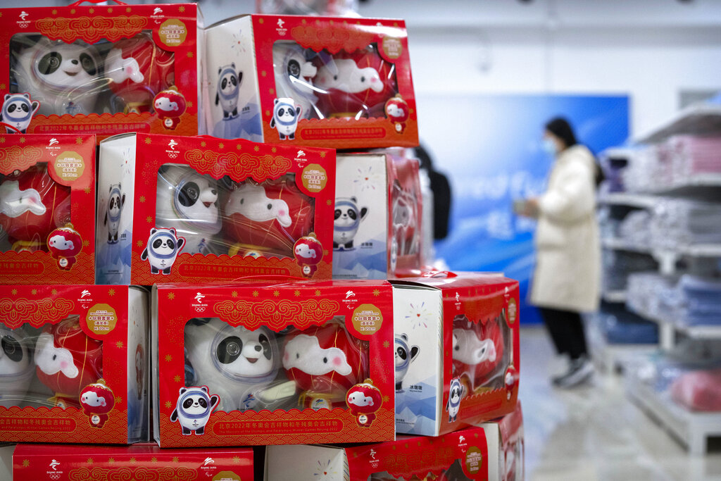 Visitors walk past merchandise for sale in a souvenir shop at a commercial plaza at the Winter Olympic Village in Beijing, Friday, Dec. 24, 2021. Organizers on Friday gave the media a look at parts of the athletes' Olympic Village for the 2022 Winter Olympics and Paralympics, which will be held beginning in February. (AP Photo/Mark Schiefelbein)