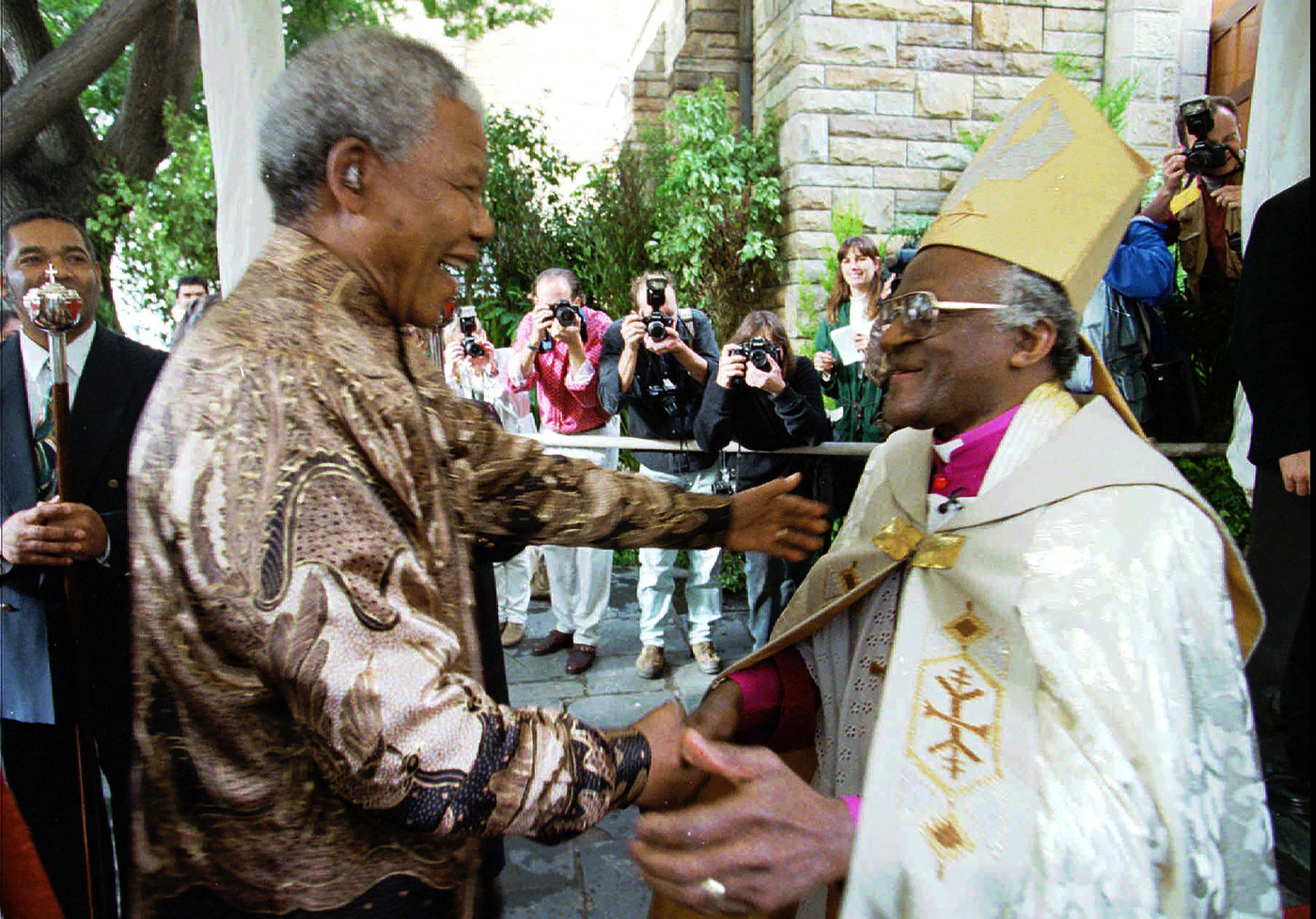 FILE - Retiring Archbishop of Cape Town Desmond Tutu, right, greets President Nelson Mandela at a service in Cape Town, Sunday June 23, 1996 held to celebrate the end of Tutu's tenure as leader of the Anglican Church in South Africa. Tutu, South Africa’s Nobel Peace Prize-winning activist for racial justice and LGBT rights and retired Anglican Archbishop of Cape Town, has died, South African President Cyril Ramaphosa announced Sunday Dec. 26, 2021. He was 90. (AP Photo/Guy Tillim, File)