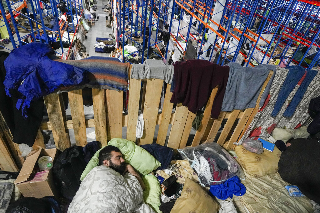 A man sleeps as migrants settle at a logistics center at the checkpoint logistics center 
