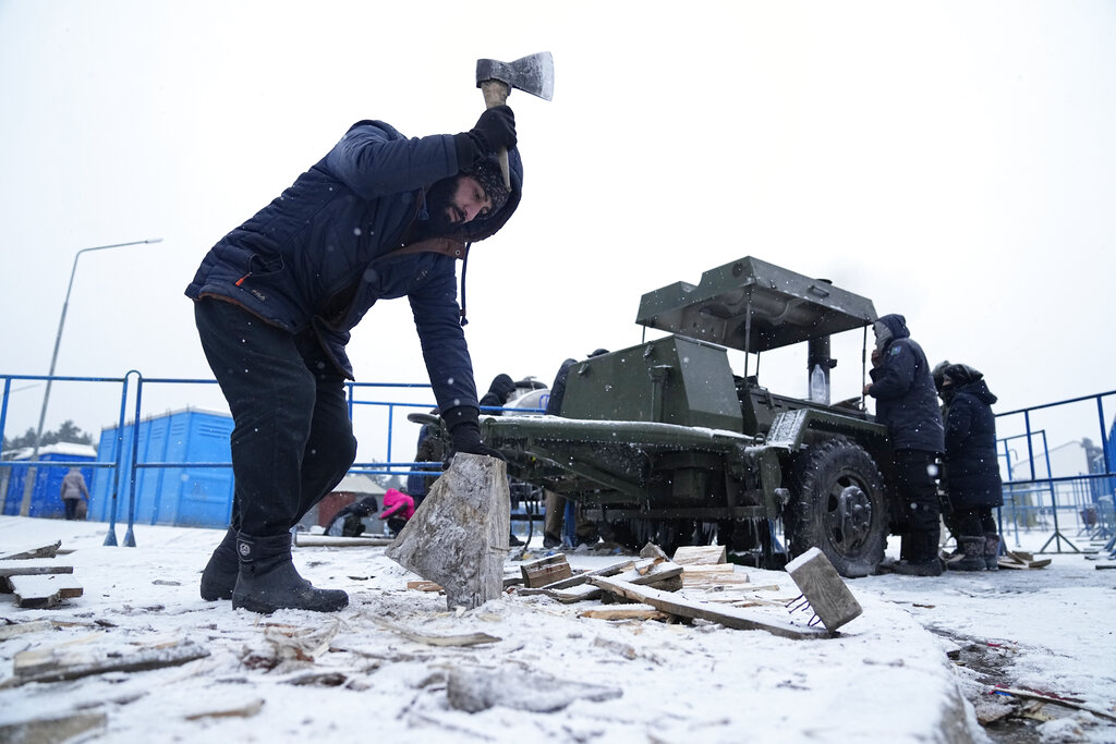 A migrant chops wood to use for cooking at the checkpoint logistics center 