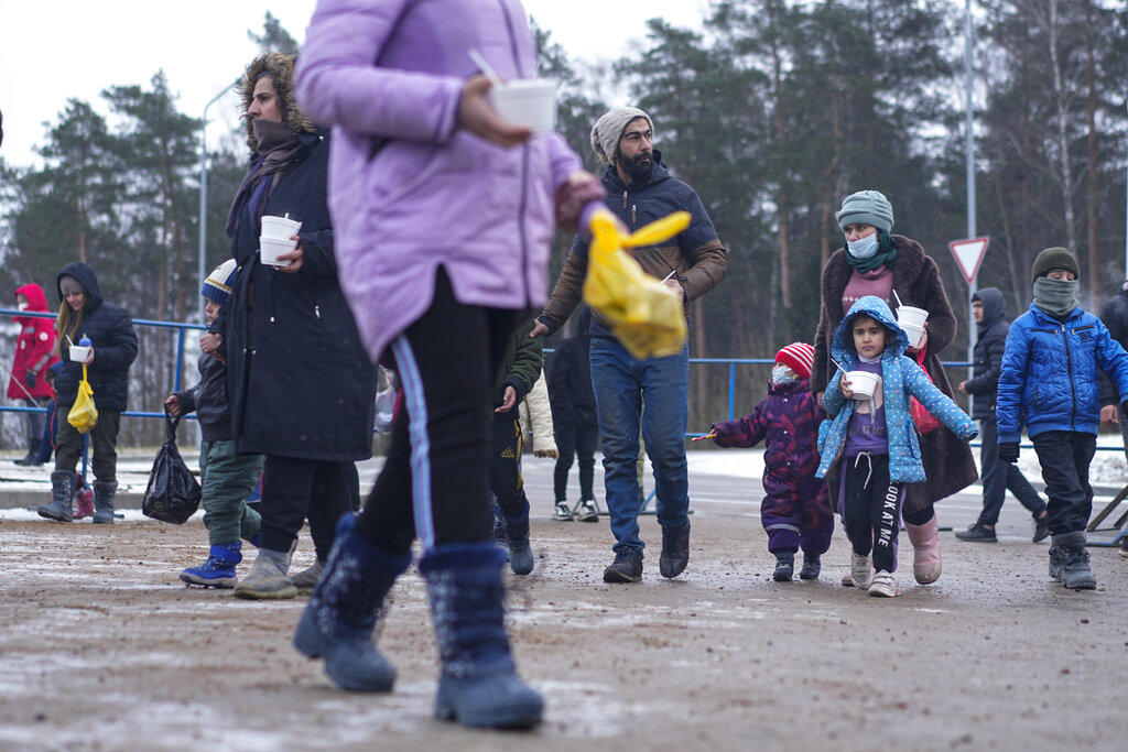 Migrants carry meal at the 