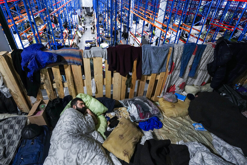 A man sleeps as migrants settle at the 