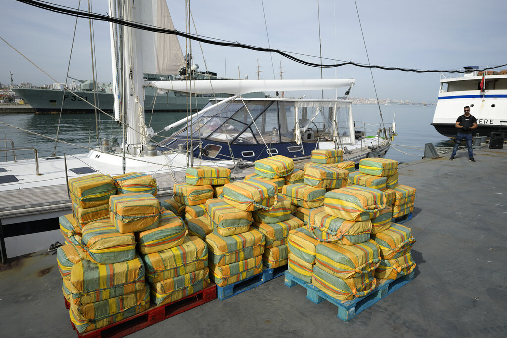 Bales of cocaine weighting some 5,2 tons and a seized yacht are displayed for the media at a Portuguese Navy base in Almada, south of Lisbon, Monday, Oct. 18, 2021. Portuguese police said Monday the seizure was the largest in Europe in recent years and the biggest in Portugal for 15 years. Police localized and intercepted the 24-meter (79-foot) yacht at sea. The operation involved police from Portugal, Spain, the Drug Enforcement Agency in the United States and the United Kingdom's National Crime Agency. (AP Photo/Armando Franca)