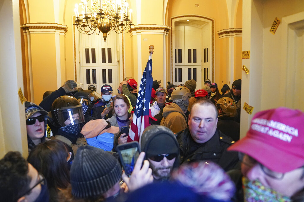 A U.S. Capitol Police officer is surrounded by rioters at a door on the East Front of the U.S. Capitol on Jan. 6, 2021, in Washington. (AP Photo/John Minchillo)