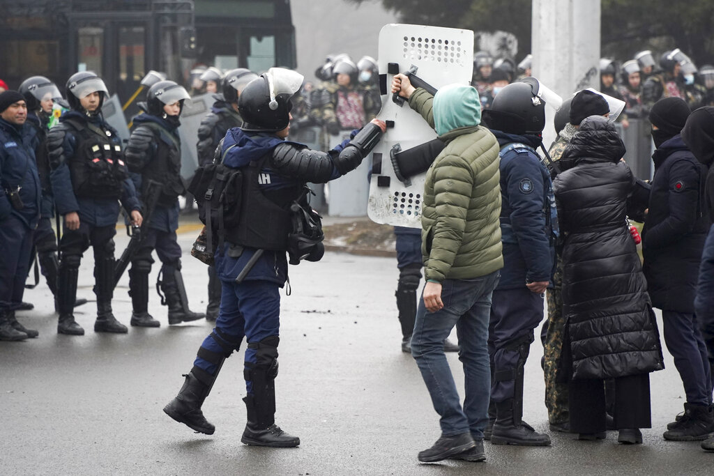 A demonstrator gives back a shield to a riot police officer during a protest in Almaty, Kazakhstan, Wednesday, Jan. 5, 2022. Demonstrators denouncing the doubling of prices for liquefied gas have clashed with police in Kazakhstan's largest city and held protests in about a dozen other cities in the country. (AP Photo/Vladimir Tretyakov)