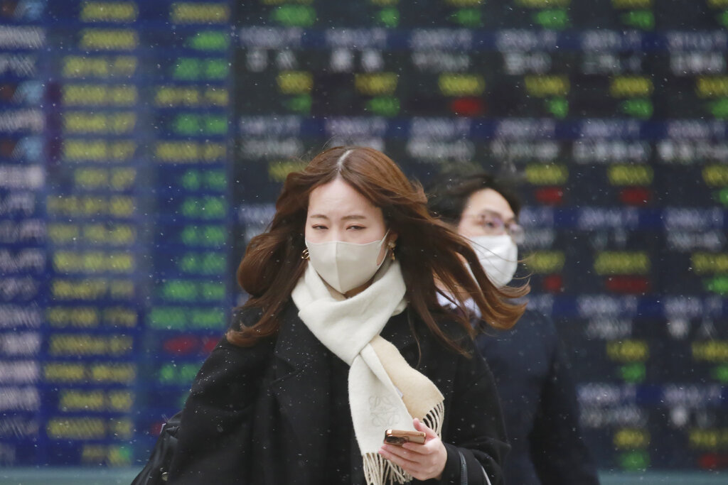 People walk by an electronic stock board of a securities firm in Tokyo, Thursday, Jan. 6, 2022. Asian stock markets followed Wall Street lower on Thursday after investors saw minutes from a Federal Reserve meeting as a sign the U.S. central bank might hike interest rates faster to cool inflation. (AP Photo/Koji Sasahara)