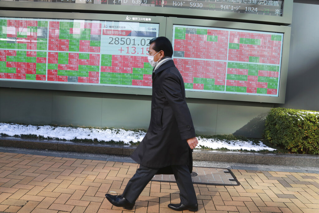 A man walks by an electronic stock board of a securities firm in Tokyo, Friday, Jan. 7, 2022.  Asian markets are mostly higher after more declines in big technology stocks pulled major indexes lower on Wall Street. Tokyo and Taiwan declined but other regional markets advanced. U.S. futures also were higher.(AP Photo/Koji Sasahara)