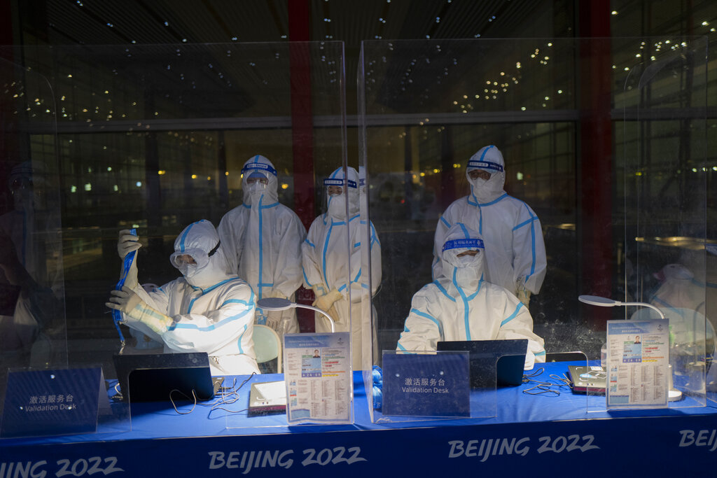 Olympic workers in hazmat suits work at a credential validation desk at the Beijing Capital International Airport ahead of the 2022 Winter Olympics in Beijing, Monday, Jan. 24, 2022. (AP Photo/Jae C. Hong)