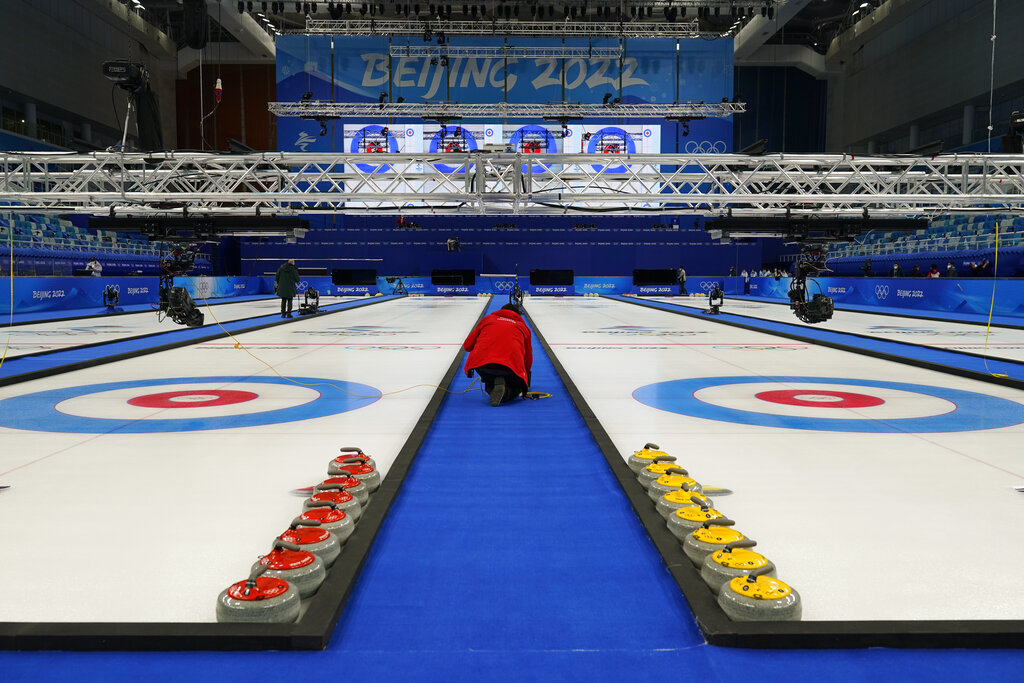 Curling rocks sit on the ice as a technician installs software at the National Aquatics Center, a venue for curling events at the 2022 Winter Olympics, Saturday, Jan. 29, 2022, in Beijing. (AP Photo/Jae C. Hong)