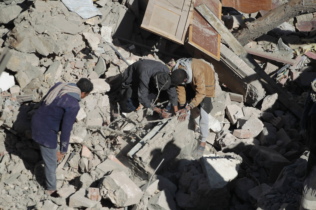 People inspect the wreckage of a building after it was damaged in Saudi-led coalition airstrikes, in Sanaa, Yemen, Tuesday, Jan. 18, 2022. The coalition fighting in Yemen announced it had started a bombing campaign targeting Houthi sites a day after a fatal attack on an oil facility in the capital of the United Arab Emirates claimed by Yemen’s Houthi rebels. It said it also struck a drone operating base in Nabi Shuaib Mountain near Sanaa. (AP Photo/Hani Mohammed)