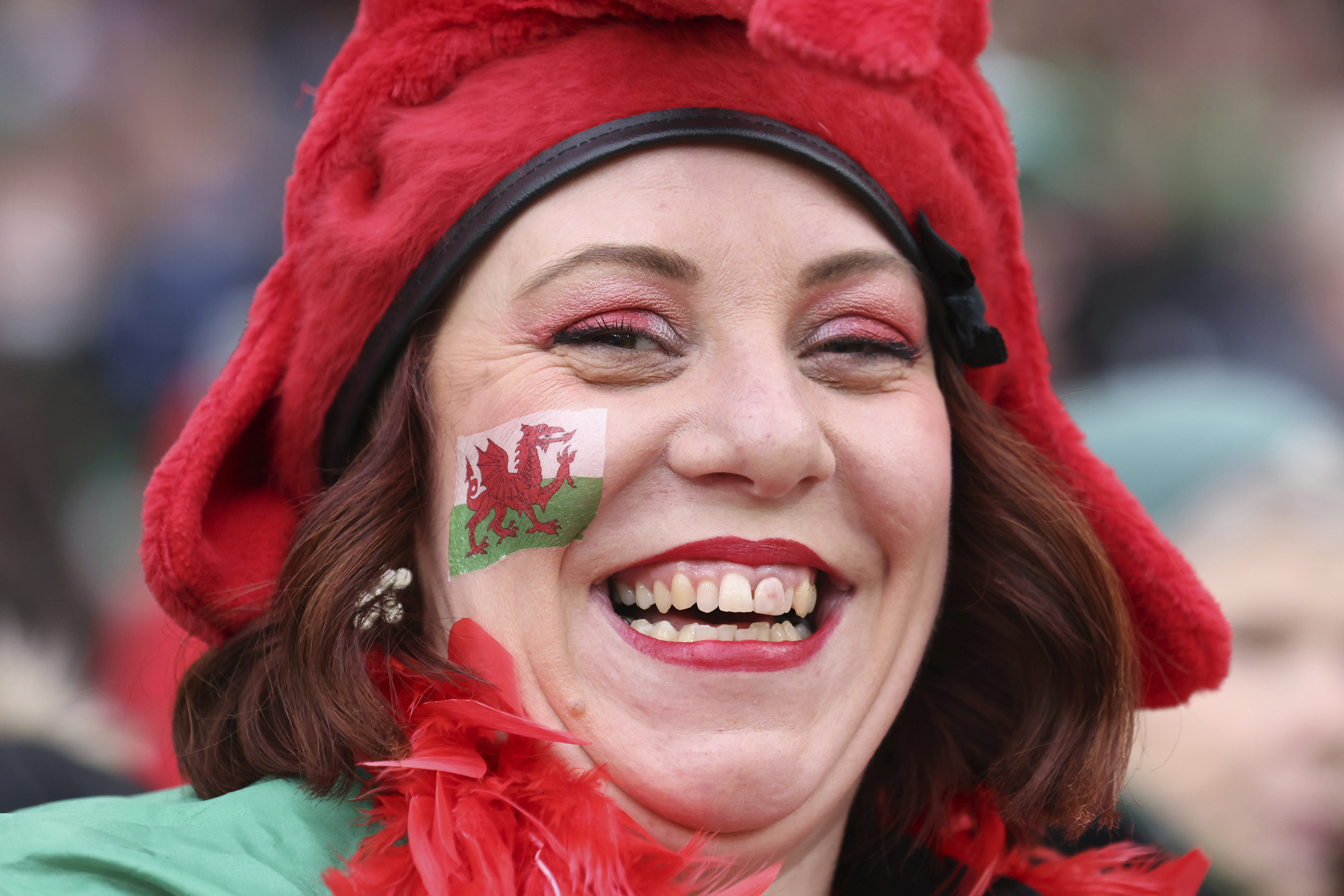 A Wales fan smiles as she waits for the start of the Six Nations rugby union match between Ireland and Wales at the Aviva stadium in Dublin, Ireland, Saturday, Feb. 5, 2022. (AP Photo/Peter Morrison)