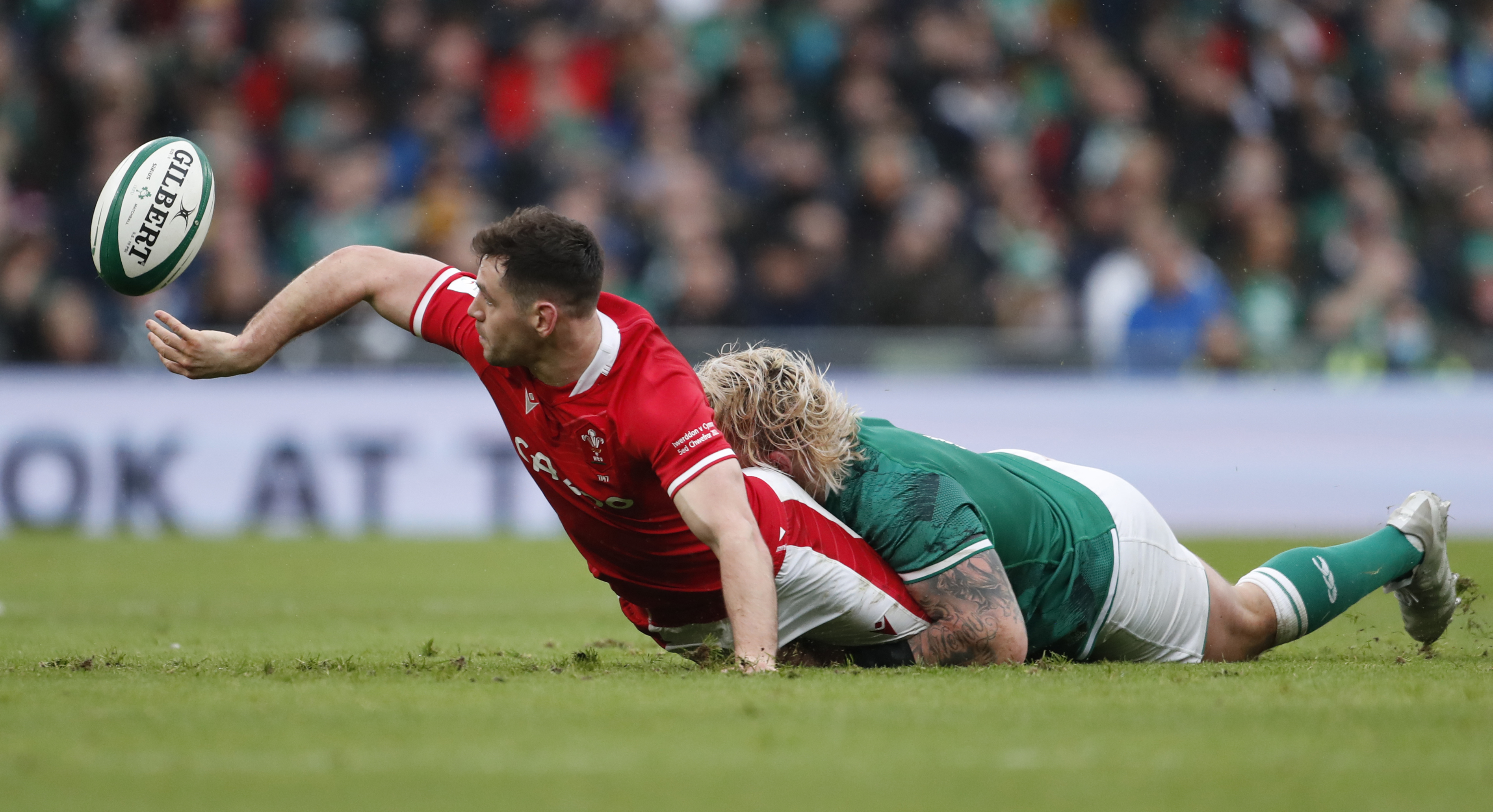 Wales' Tomos Williams, left, passes the ball as Ireland's Andrew Porter tackles during the Six Nations rugby union match between Ireland and Wales at the Aviva stadium in Dublin, Ireland, Saturday, Feb. 5, 2022. (AP Photo/Peter Morrison)