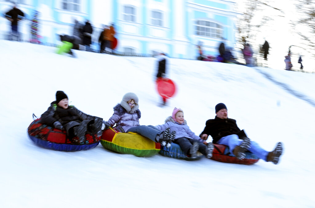 People enjoy sledding in a park in St. Petersburg, Russia, Saturday, Jan. 1, 2022. (AP Photo/Dmitri Lovetsky)