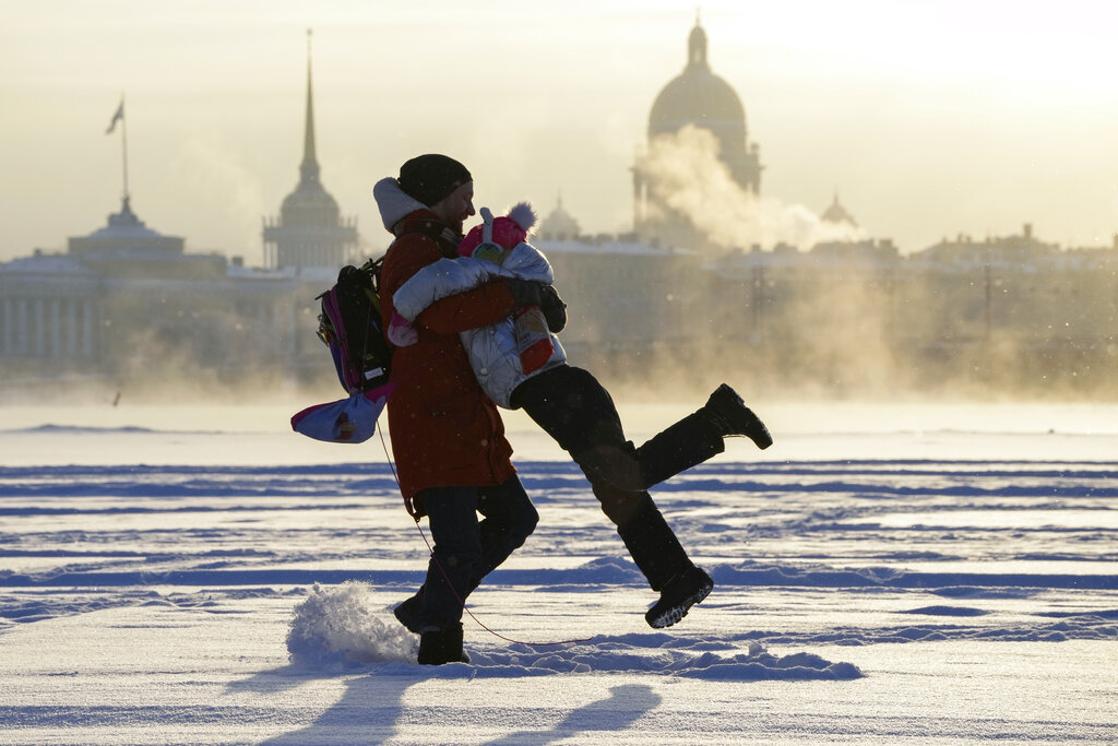 A man plays with his daughter on the ice of the Neva River in St. Petersburg, Russia, Tuesday, Jan. 11, 2022. (AP Photo/Dmitri Lovetsky)