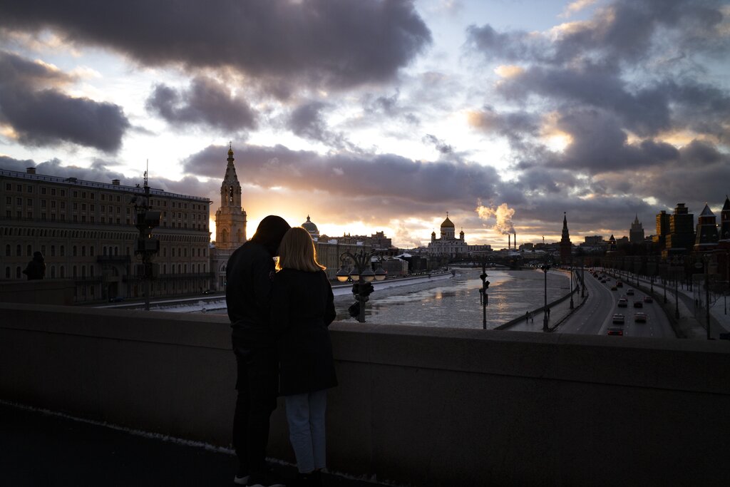 A couple watch the sunset over the frozen Moscow River and the Kremlin,  in Moscow, Russia, Sunday, Jan. 16, 2022. (AP Photo/Alexander Zemlianichenko)