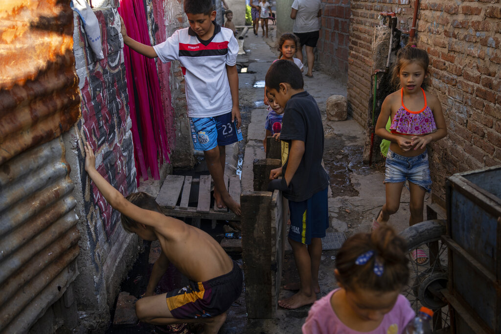 Children play in one of the corridors in Puerta 8, a low income neighborhood north of Buenos Aires, Argentina, Wednesday, Feb. 9, 2022, where contaminated cocaine may have been sold. A batch of that toxic cocaine has killed at least 23 people and hospitalized many more, according to police. (AP Photo/Rodrigo Abd)