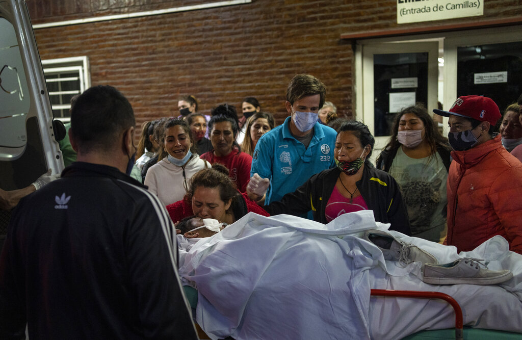 Family members watch as a relative who has been hospitalized for days after consuming toxic cocaine, is transported to another hospital, outside the Bocalandro Hospital, in the Puerta 8 neighborhood, a suburb north of Buenos Aires, Argentina, Saturday, Feb. 5, 2022. A batch of cocaine has killed at least 23 people and hospitalized many more in Argentina, according to police. (AP Photo/Rodrigo Abd)