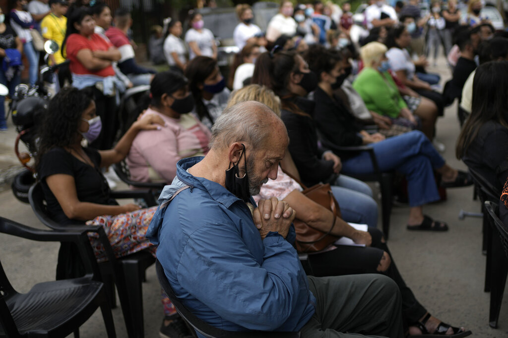 People attend an outdoor Catholic Mass held in remembrance of those who recently died from consuming toxic cocaine and for those who were severely sickened by the contaminated drug, in the Puerta 8 neighborhood, a suburb north of Buenos Aires, Argentina, Saturday, Feb. 5, 2022.  A batch of cocaine has killed at least 23 people and hospitalized many more in Argentina, according to police. (AP Photo/Rodrigo Abd)