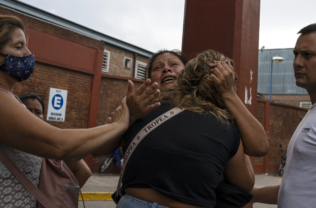 A woman, facing the camera, is consoled after learning her brother died from consuming toxic cocaine, outside the Bocalandro Hospital near the 