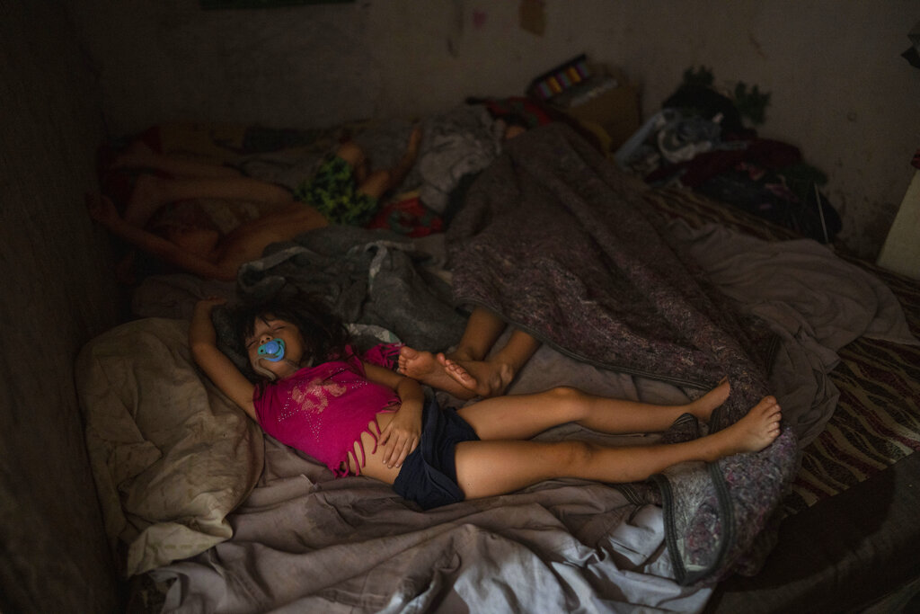 Daughters of Soledad Campos sleep inside her home where police detained her 18-year-old son as a suspect in connection with the sale of contaminated cocaine, in the Puerta 8 suburb north of Buenos Aires, Argentina, Friday, Feb. 4, 2022. A batch of cocaine has killed at least 23 people and hospitalized many more in Argentina, according to police. (AP Photo/Rodrigo Abd)