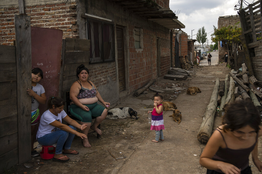 Residents sit outside their homes in the Puerta 8 suburb north of Buenos Aires, Argentina, where police say contaminated cocaine may have been sold, Friday, Feb. 4, 2022. A batch of cocaine has killed at least 23 people and hospitalized many more in Argentina, according to police. (AP Photo/Rodrigo Abd)
