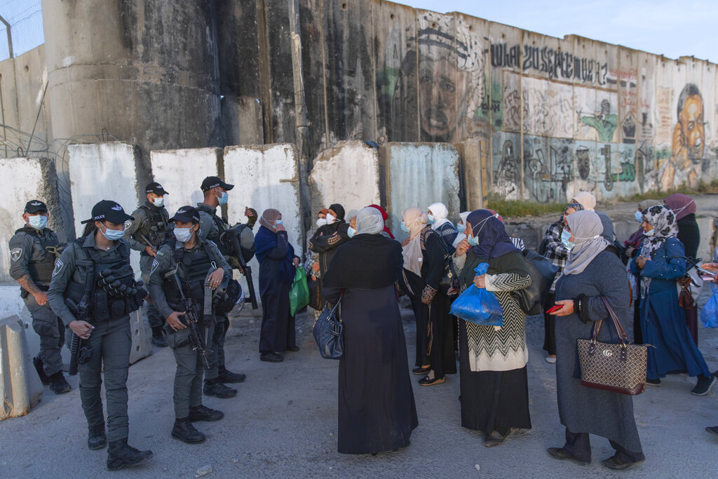 Palestinian women wait to cross the Qalandia checkpoint between the West Bank city of Ramallah and Jerusalem, to attend the first Friday prayers in al-Aqsa mosque, during the Muslim holy month of Ramadan, Friday, April 16, 2021. One of the world's best-known human rights groups says Israel is guilty of the international crimes of apartheid and persecution. Human Rights Watch cites discriminatory policies toward Palestinians within Israel's own borders and in the occupied territories. In so doing, the New York-based group joins a growing number of commentators and rights groups that consider Israel and the territories as a single entity in which Palestinians are denied basic rights that are granted to Jews. (AP Photo/Nasser Nasser)