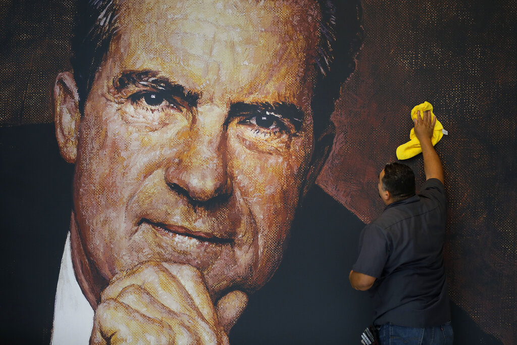 In this Wednesday, Oct. 5, 2016 photo, Tayron Santos cleans the newly-installed wall mural of former President Richard Nixon in the lobby area of the Richard Nixon Presidential Library and Museum in Yorba Linda, Calif. The museum will reopen Friday, Oct. 14, following a $15 million makeover aimed at bringing the country’s 37th president closer to younger generations less familiar with his groundbreaking trip to China or the Watergate scandal. (AP Photo/Jae C. Hong)