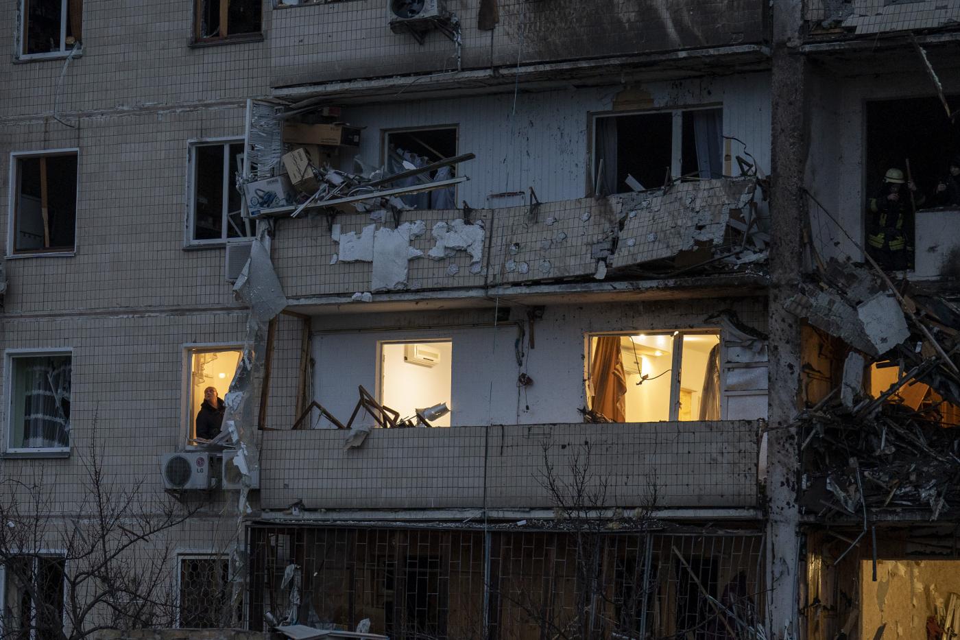 A fire-fighter inspects the damage at a building following a rocket attack on the city of Kyiv, Ukraine, Friday, Feb. 25, 2022. (AP Photo/Emilio Morenatti)