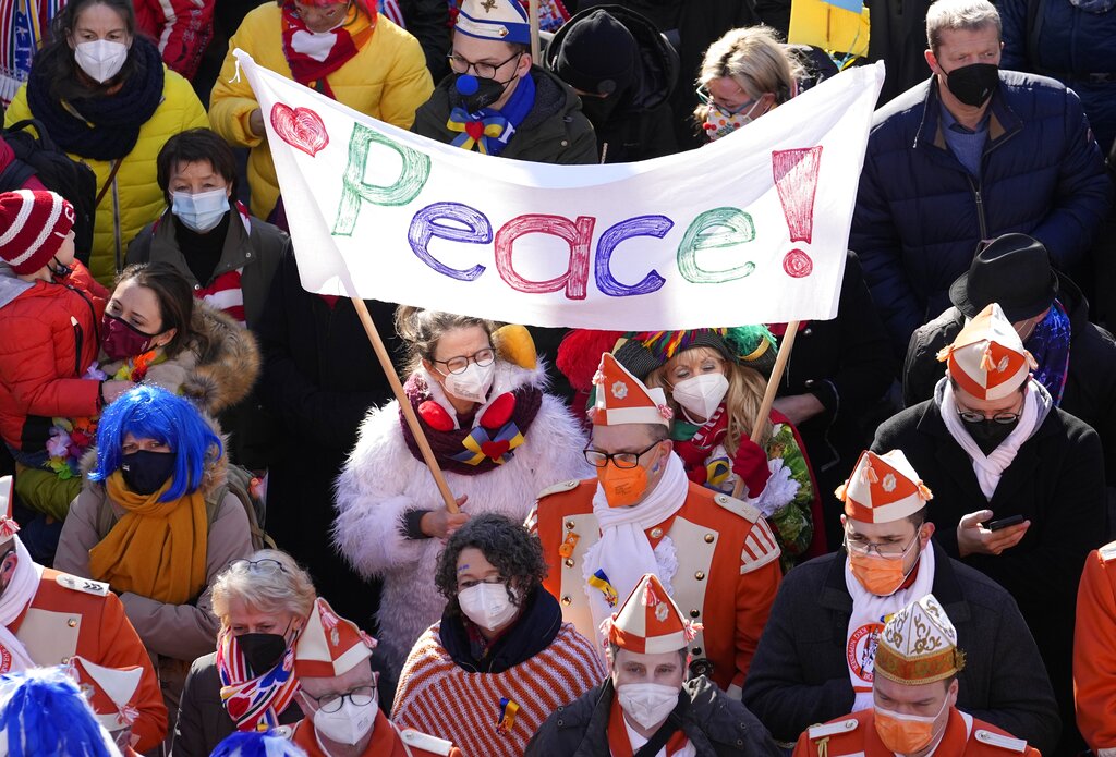Carnival revelers show signs for peace in Cologne, Germany, during a peace march of tens of thousands against the war in Ukraine on Shrove Monday, Feb. 28, 2022. The traditional carnival Rose Monday Parade in Cologne was cancelled due to Russia's war in Ukraine. Instead of the parade, the political carnival floats were placed in the city followed by a peace protest of revelers. (AP Photo/Martin Meissner)