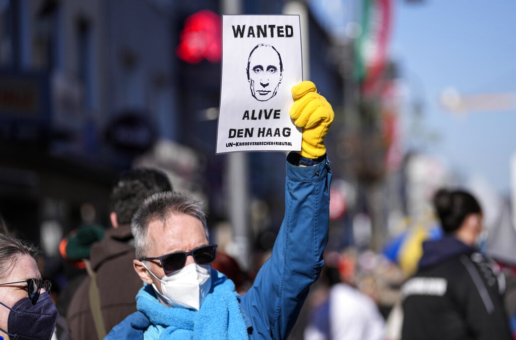 A man holds a sign demanding Putin for The Hague in Cologne, Germany, during a peace march against the war in Ukraine on Shrove Monday, Feb. 28, 2022. The traditional carnival Rose Monday Parade in Cologne was cancelled due to Russia's war in Ukraine. Instead of the parade, the political carnival floats were placed in the city followed by a peace protest of revelers. (AP Photo/Martin Meissner)