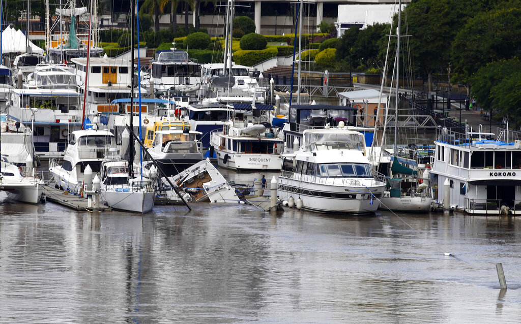 A partially sunken boat is seen at a jetty on a river in Brisbane, Australia, Wednesday, March 2, 2022. Tens of thousands of people had been ordered to evacuate their homes and many more had been told to prepare to flee as parts of Australia's southeast coast are inundated by the worst flooding in decades. (AP Photo/Tertius Pickard)