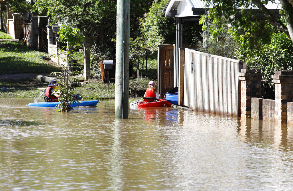 Residents on canoes are seen outside their flooded home in Brisbane, Australia, Tuesday, March 1, 2022. Tens of thousands of people had been ordered to evacuate their homes and many more had been told to prepare to flee as parts of Australia's southeast coast are inundated by the worst flooding in decades. (AP Photo/Tertius Pickard)