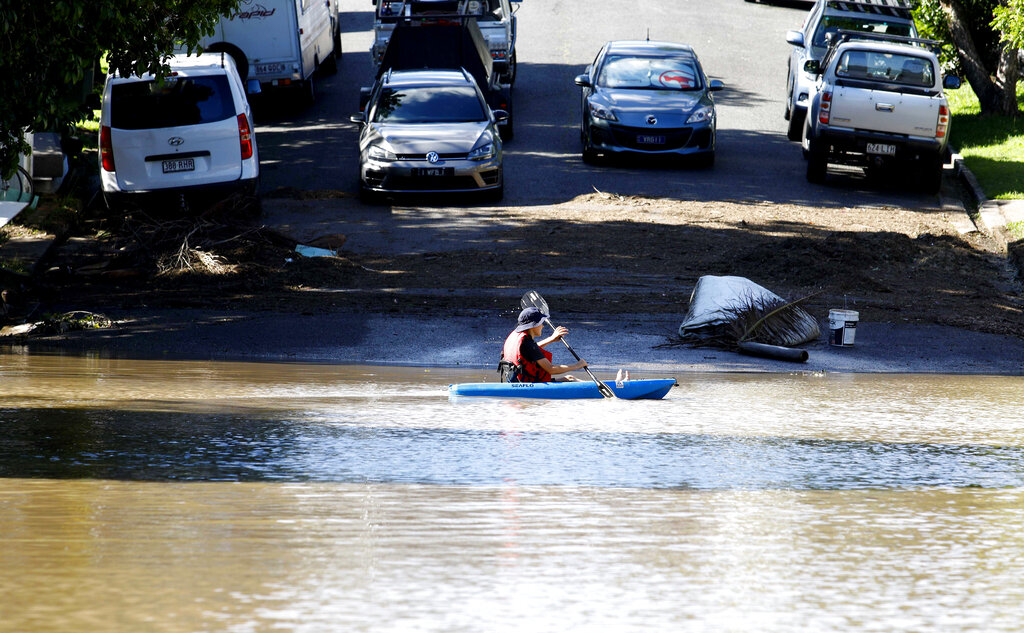 A resident paddles a canoe in flood waters in Brisbane, Australia, Tuesday, March 1, 2022. Tens of thousands of people had been ordered to evacuate their homes and many more had been told to prepare to flee as parts of Australia's southeast coast are inundated by the worst flooding in decades. (AP Photo/Tertius Pickard)