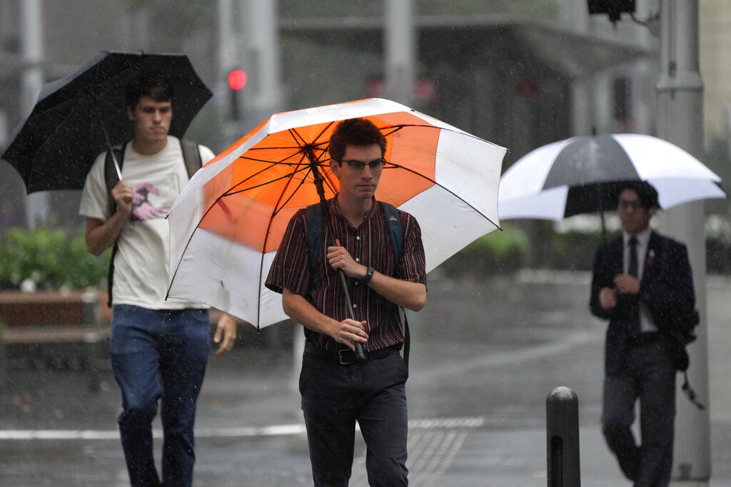 Pedestrians use umbrellas to shield the rain in Sydney, Wednesday, March 2, 2022, as parts of Australia's southeast coast were inundated by the worst flooding in more than a decade. Floodwaters are moving south into New South Wales from ç state in the worst disaster in the region since what was described as a once-in-a-century event in 2011. (AP Photo/Rick Rycroft)