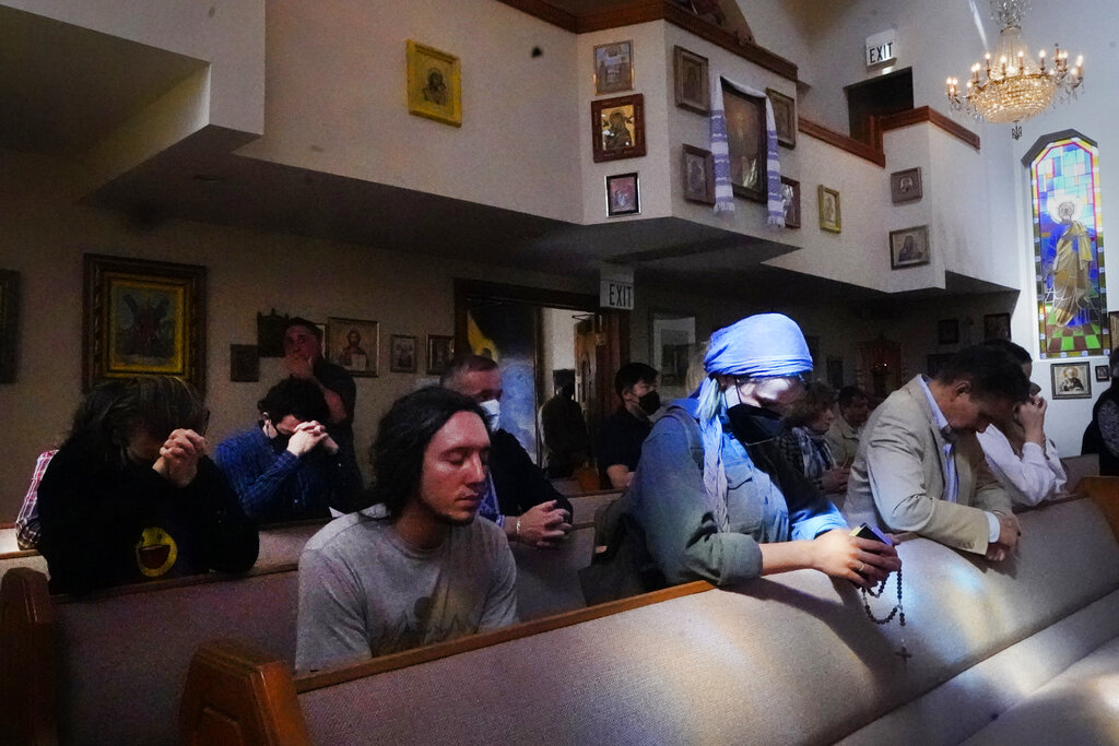Members of the Ukrainian community and parishioners pray during a Mass service at Saint Andrew Ukrainian Orthodox Church of Los Angeles Sunday, Feb. 27, 2022. In Los Angeles where Russians, Ukrainians, Belarusians, Romanians, Georgians, Moldovians, Estonians and Lithuanians live, work, pray, shop and eat together, the Ukrainian conflict has turned into a personal, emotional, even painful affair for many. (AP Photo/Damian Dovarganes)