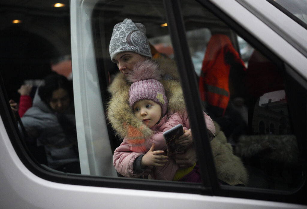 A woman and child, who have fled Ukraine, get out of a van after arriving at the train station in Przemysl, Poland, Tuesday, March 8, 2022. (AP Photo/Daniel Cole)
