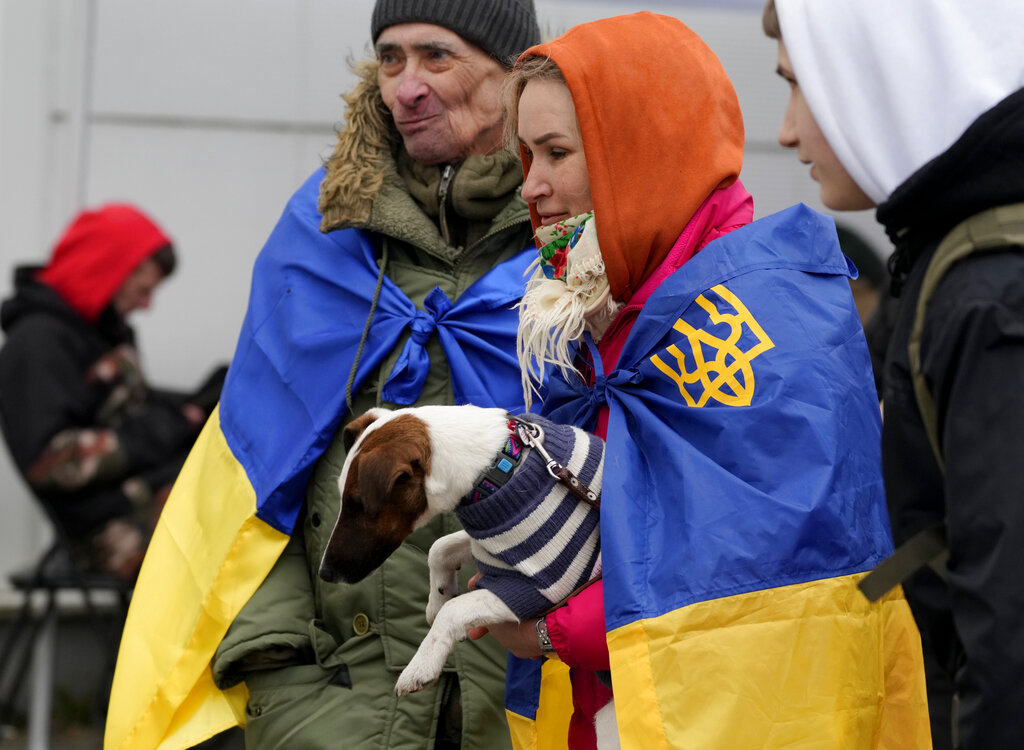 A woman and a man, wrapped in Ukrainian flags hold a dog as they arrive at a humanitarian aid center, for displaced persons fleeing Ukraine, in Przemysl, Poland, Tuesday, March 8, 2022. U.N. officials said Tuesday that the Russian onslaught has forced more than 2 million people to flee Ukraine. (AP Photo/Czarek Sokolowski)