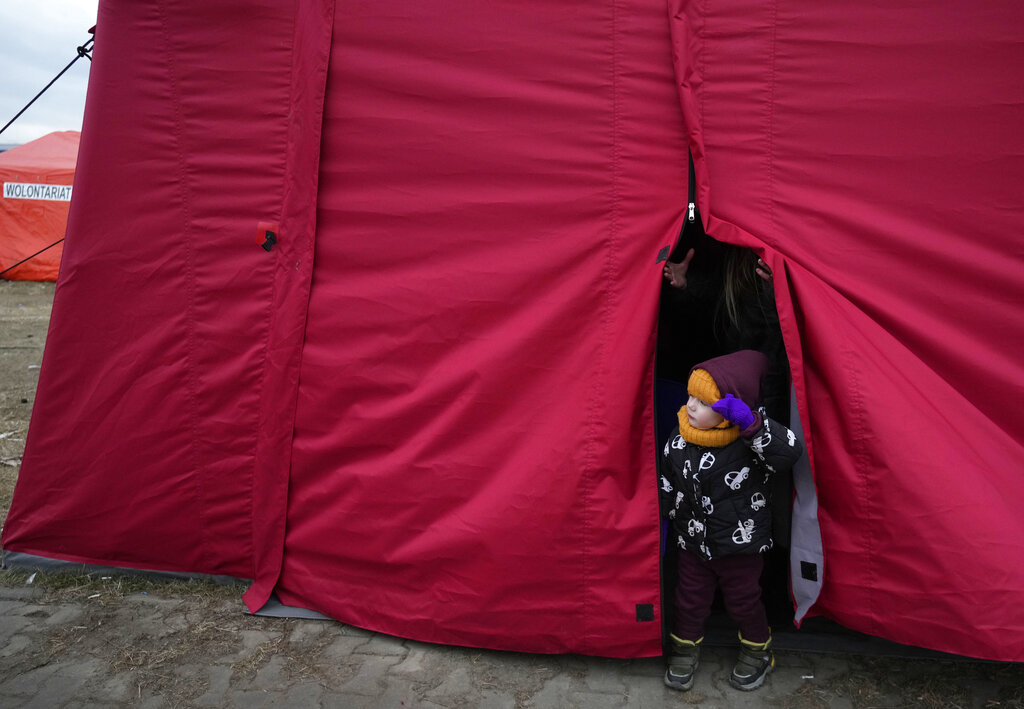 A small child and his companion look out from the front flap of a tent as they rest in a humanitarian aid center, for displaced persons fleeing Ukraine, in Przemysl, Poland, Tuesday, March 8, 2022. U.N. officials said Tuesday that the Russian onslaught has forced more than 2 million people to flee Ukraine. (AP Photo/Czarek Sokolowski)