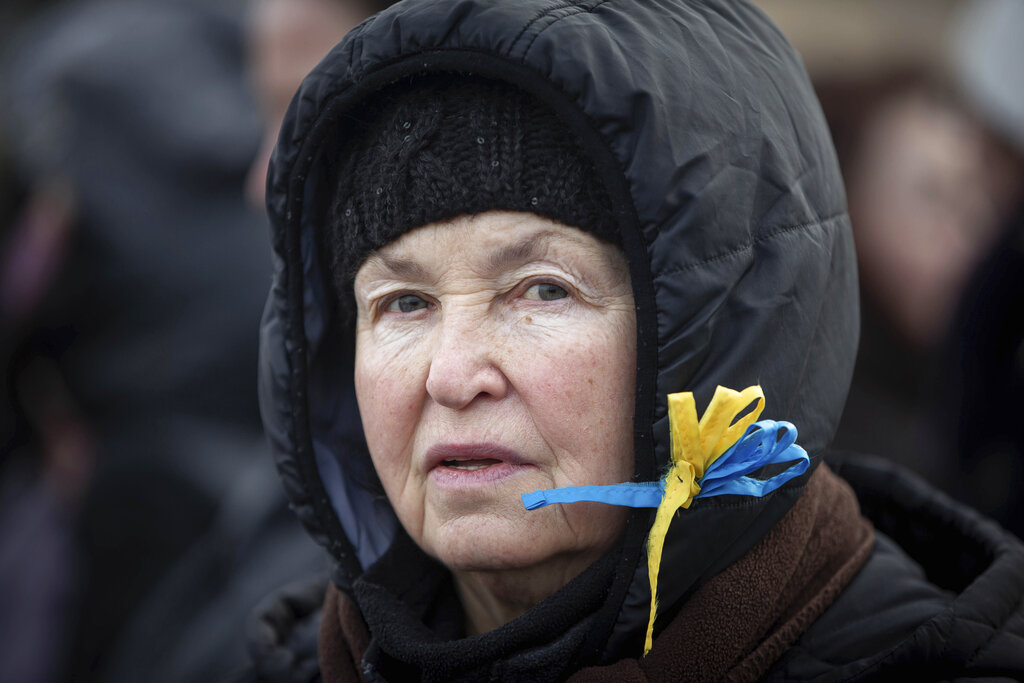 A woman wearing a ribbon with the colors of the Ukrainian flag waits to board a bus at the border crossing in Medyka, Poland, Poland, Tuesday, March 8, 2022. Russia's invasion of Ukraine has set off the largest mass migration in Europe in decades, with more than 1.5 million people having crossed from Ukraine into neighboring countries. (AP Photo/Visar Kryeziu)