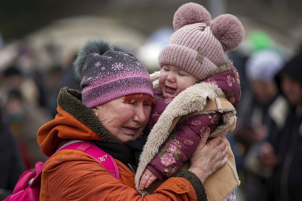 A woman holding a child cries after fleeing from Ukraine and arriving at the border crossing in Medyka, Poland, Monday, March 7, 2022. (AP Photo/Visar Kryeziu)