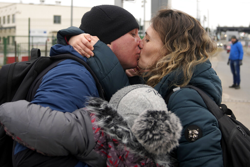 A man kisses his wife after she crossed the border from Ukraine, with their kids, in Medyka, Poland, Sunday, March 6, 2022. The number of Ukrainians forced from their country increased to 1.5 million and the Kremlin's rhetoric grew, with Russian President Vladimir Putin warning that Ukrainian statehood is in jeopardy. He likened the West's sanctions on Russia to 